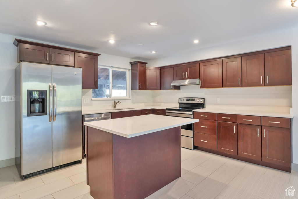 Kitchen with light tile flooring, a center island, stainless steel appliances, and sink