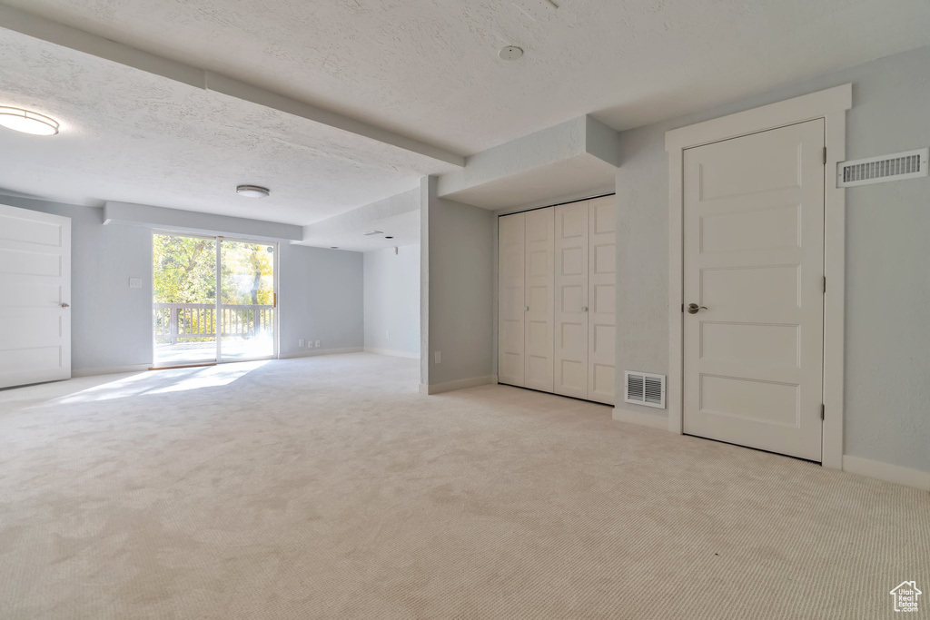 Additional living space featuring a textured ceiling and light colored carpet