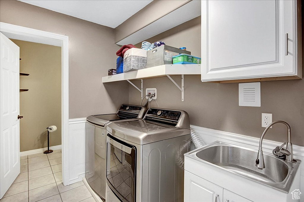 Laundry area with washer hookup, washer and clothes dryer, sink, light tile floors, and cabinets