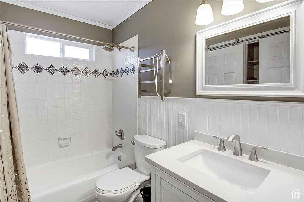 Full bathroom featuring shower / bathtub combination with curtain, vanity, ornamental molding, and toilet