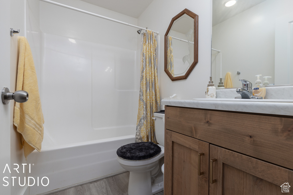 Full bathroom featuring wood-type flooring, shower / tub combo, toilet, and vanity