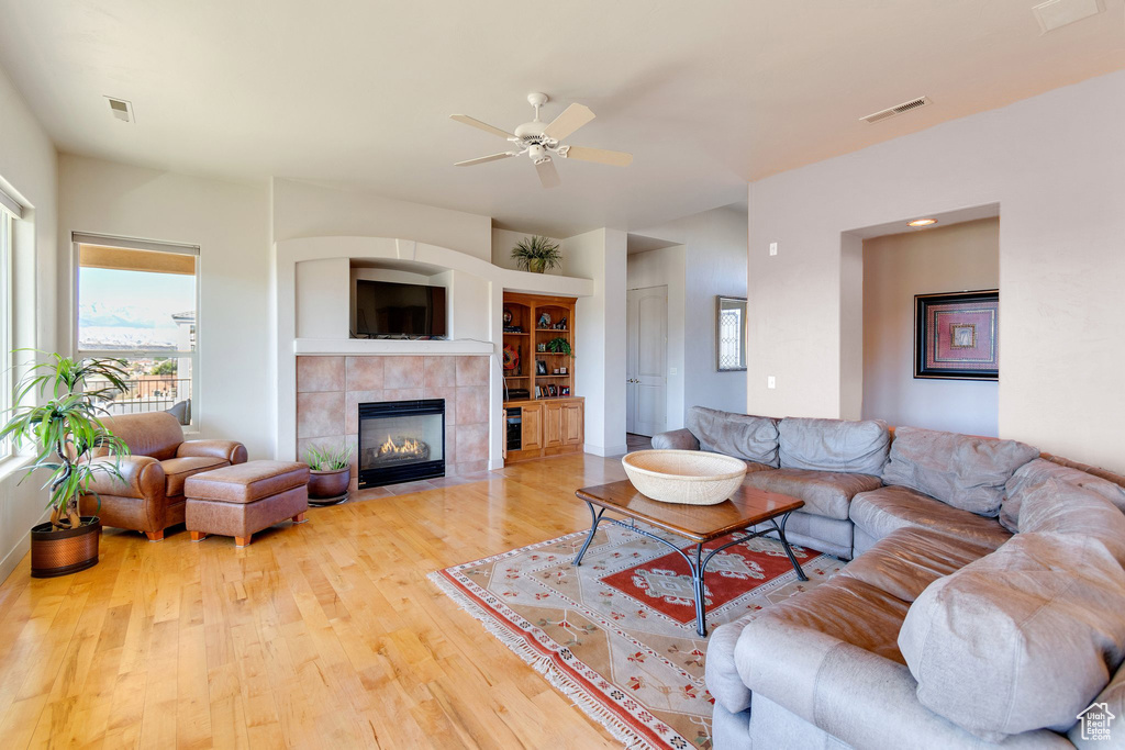 Living room featuring a tile fireplace, light hardwood / wood-style floors, and ceiling fan