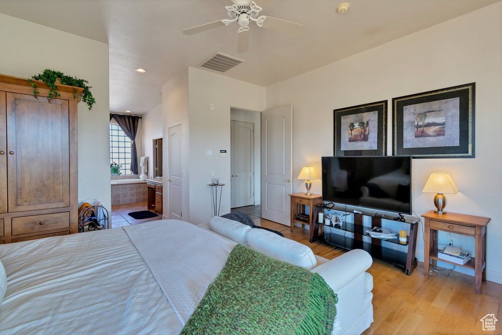 Bedroom with light hardwood / wood-style floors, ensuite bath, and ceiling fan