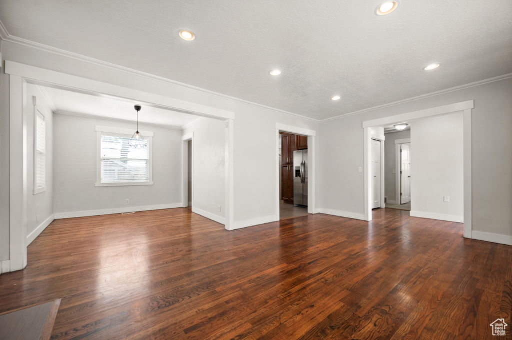 Spare room with a chandelier, ornamental molding, and dark hardwood / wood-style floors