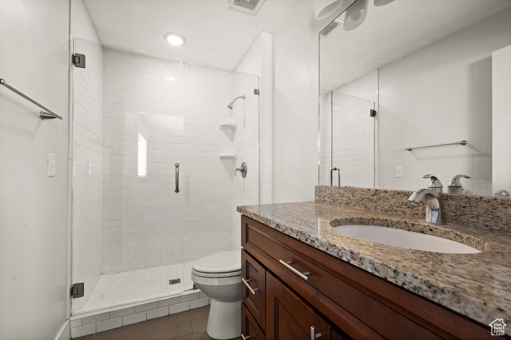 Bathroom with an enclosed shower, vanity, toilet, and tile floors