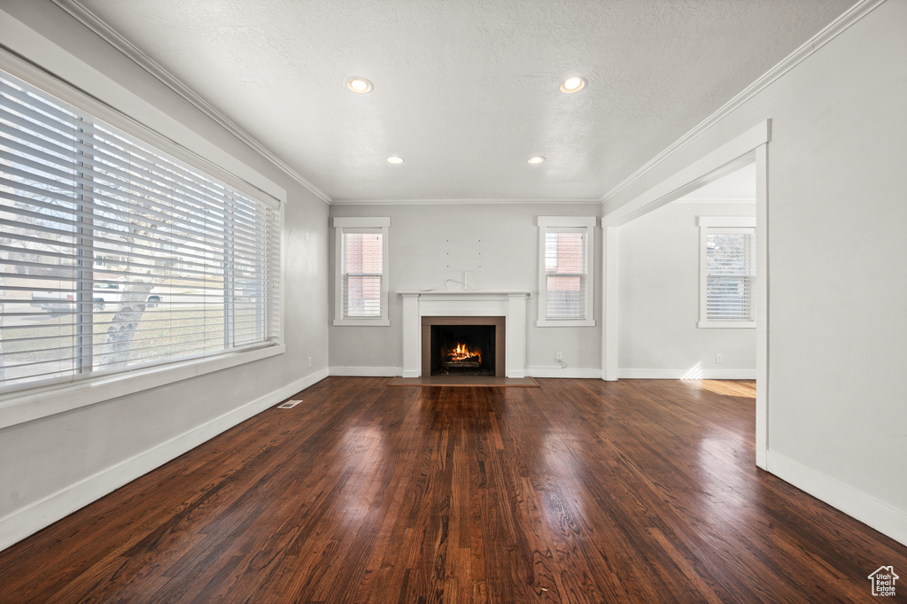 Unfurnished living room featuring ornamental molding and dark hardwood / wood-style flooring