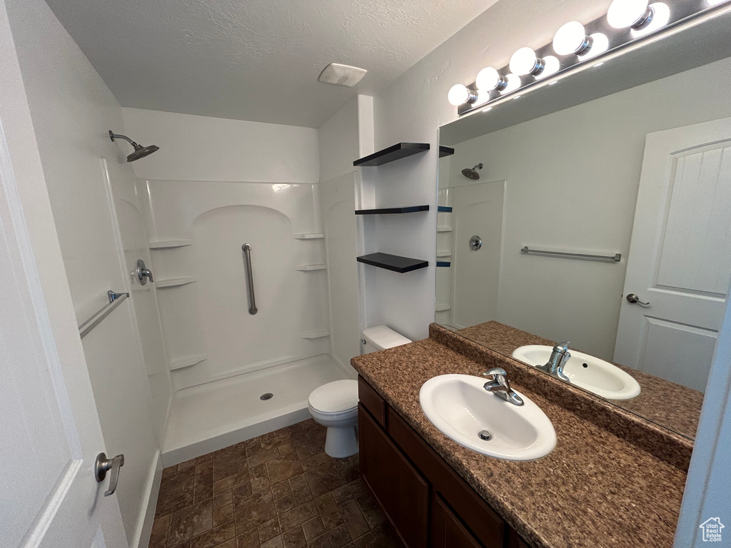 Bathroom featuring walk in shower, vanity, toilet, and tile flooring