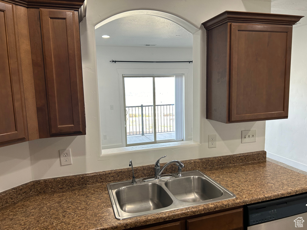 Kitchen with sink, dark brown cabinets, and dishwasher