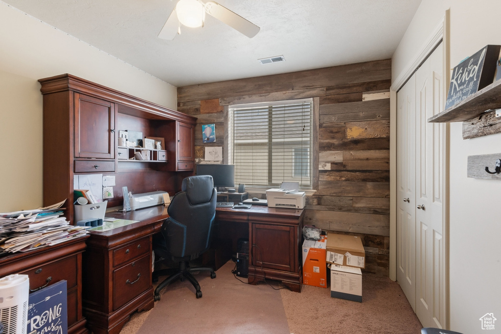Carpeted office with ceiling fan and wooden walls