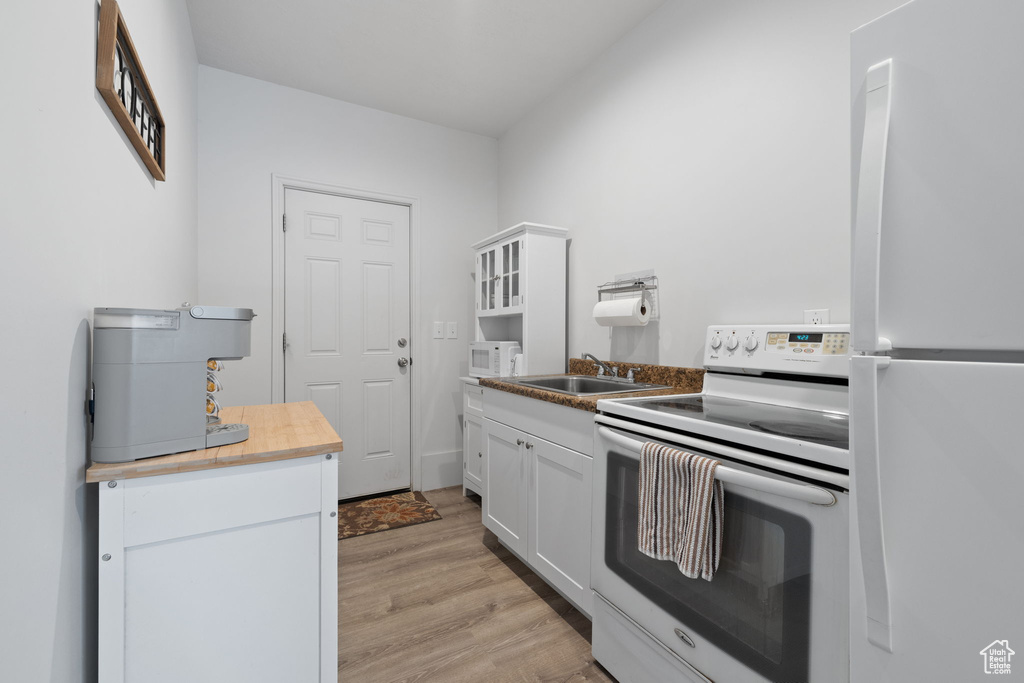 Kitchen featuring sink, light hardwood / wood-style flooring, white appliances, and white cabinets