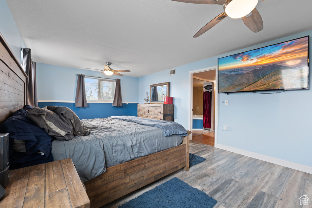 Bedroom featuring a spacious closet, connected bathroom, hardwood / wood-style floors, and ceiling fan