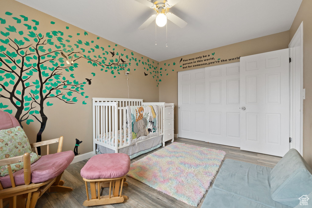 Bedroom with hardwood / wood-style flooring, a crib, and ceiling fan