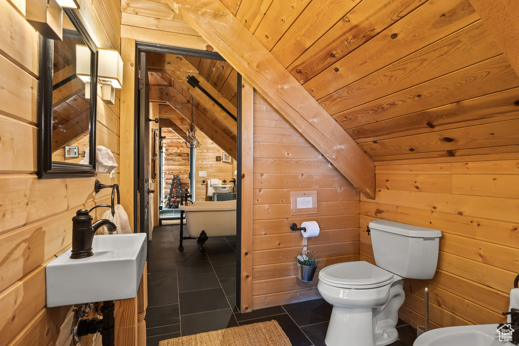 Bathroom with wood walls, tile flooring, toilet, and wooden ceiling