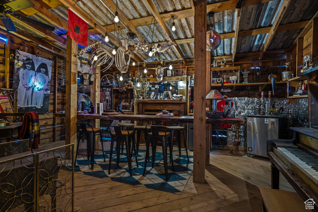 Interior space with dark hardwood / wood-style flooring, vaulted ceiling, and bar area