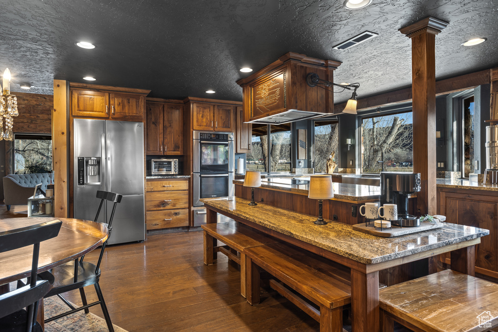Kitchen with dark hardwood / wood-style floors, stainless steel appliances, a textured ceiling, and light stone counters
