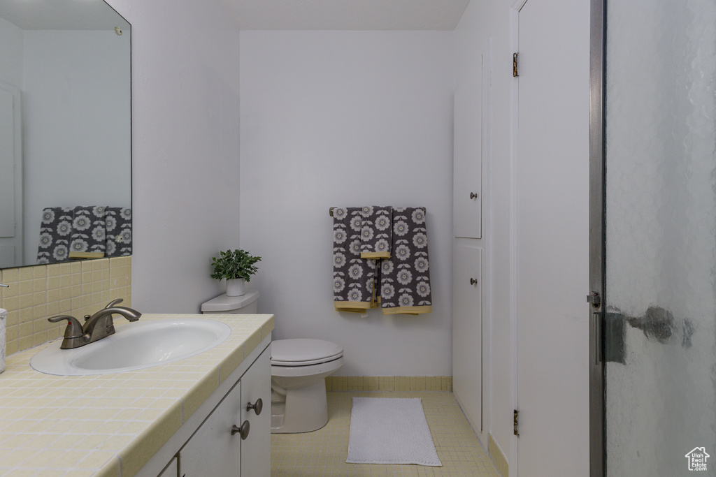 Bathroom with backsplash, toilet, large vanity, and tile floors
