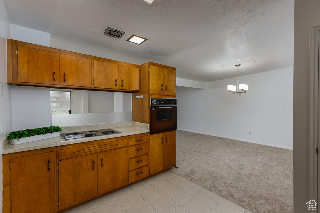 Kitchen featuring a notable chandelier, black oven, decorative light fixtures, and light tile flooring