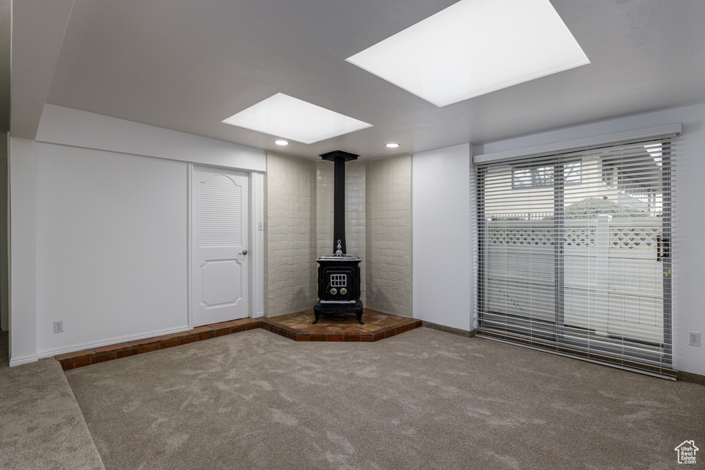 Unfurnished room featuring a wood stove and dark colored carpet