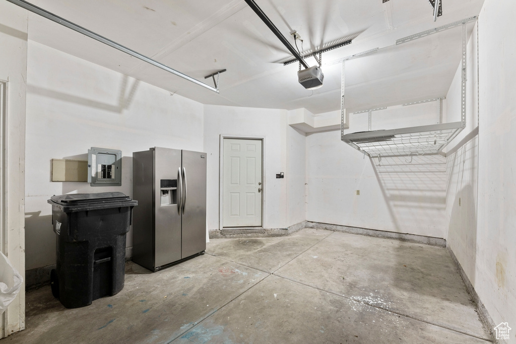 Garage with stainless steel fridge and a garage door opener