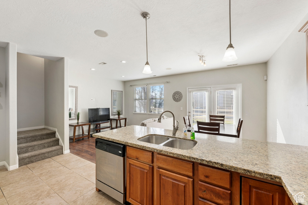 Kitchen with decorative light fixtures, dishwasher, light tile floors, and sink