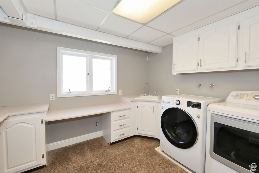 Laundry area featuring dark colored carpet, sink, cabinets, and washer and clothes dryer