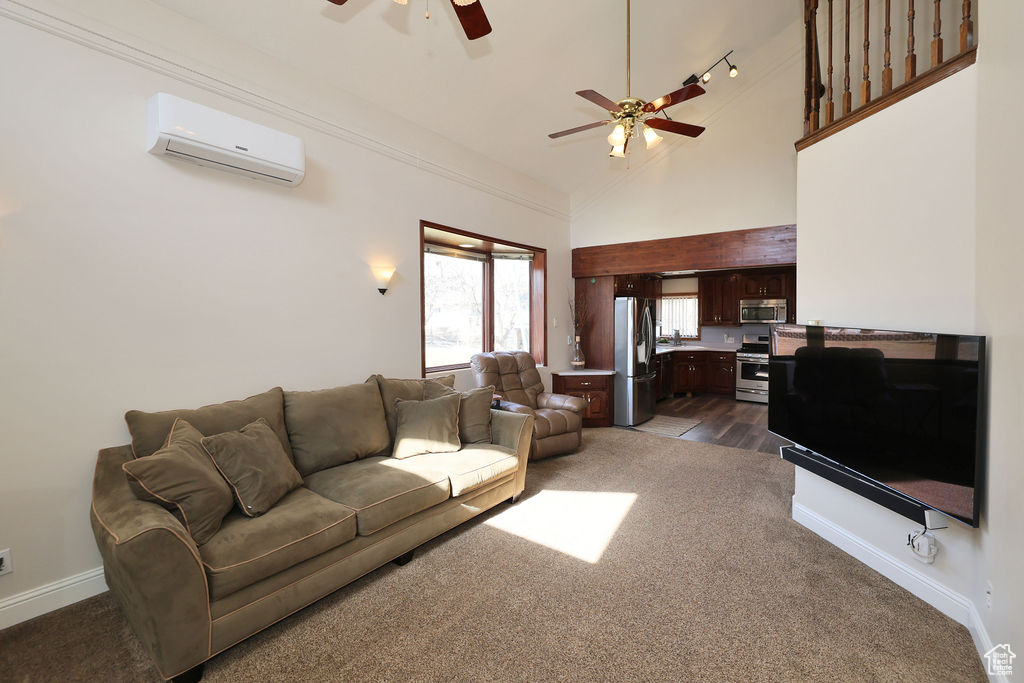 Living room featuring high vaulted ceiling, a wall unit AC, hardwood / wood-style floors, and ceiling fan