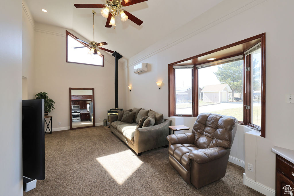Carpeted living room featuring a wall mounted AC, ornamental molding, a towering ceiling, a wood stove, and ceiling fan