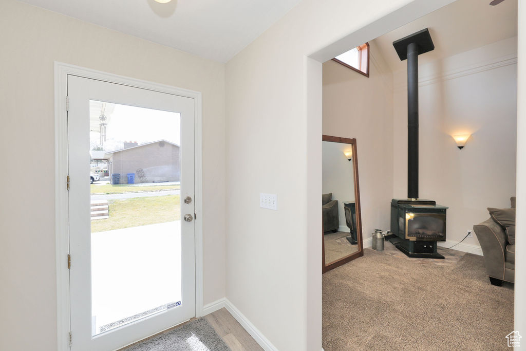Doorway to outside with light colored carpet and a wood stove