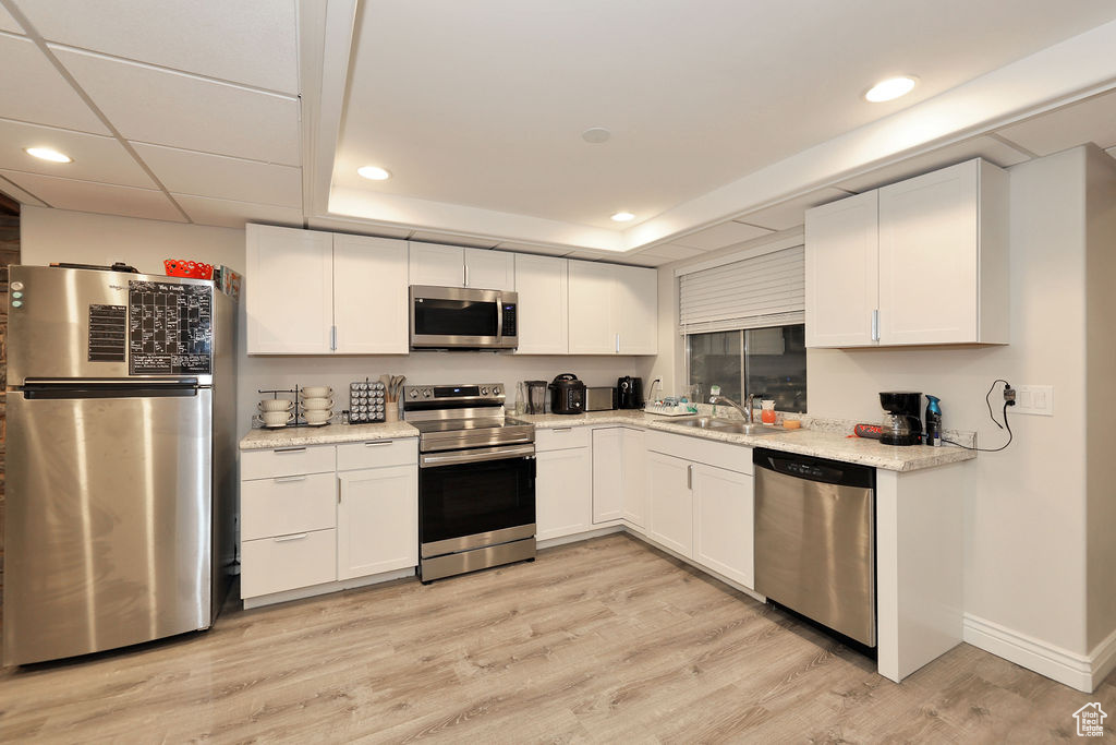 Kitchen featuring white cabinets, stainless steel appliances, sink, and light hardwood / wood-style flooring