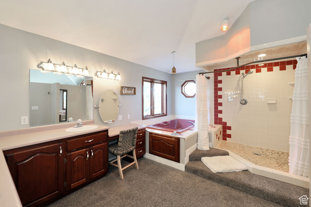 Bathroom featuring lofted ceiling, shower with separate bathtub, and oversized vanity