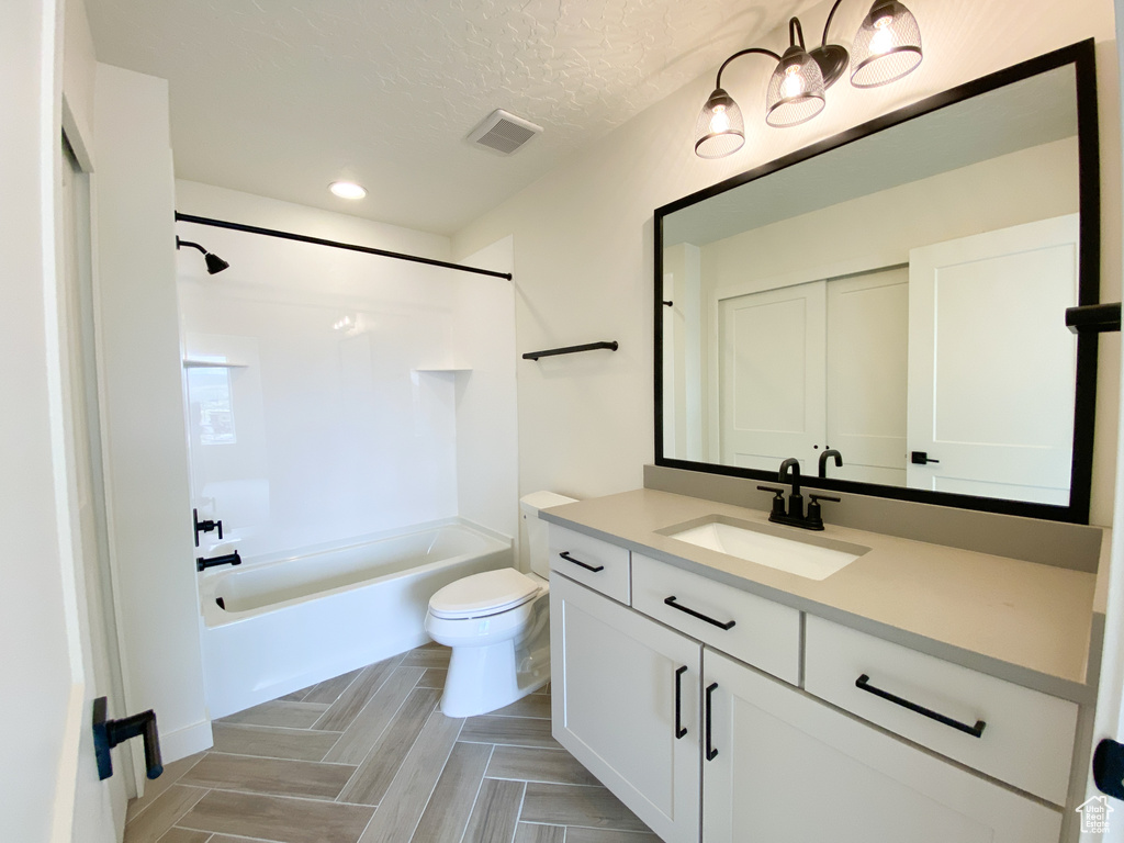 Full bathroom featuring shower / tub combination, oversized vanity, a textured ceiling, and toilet