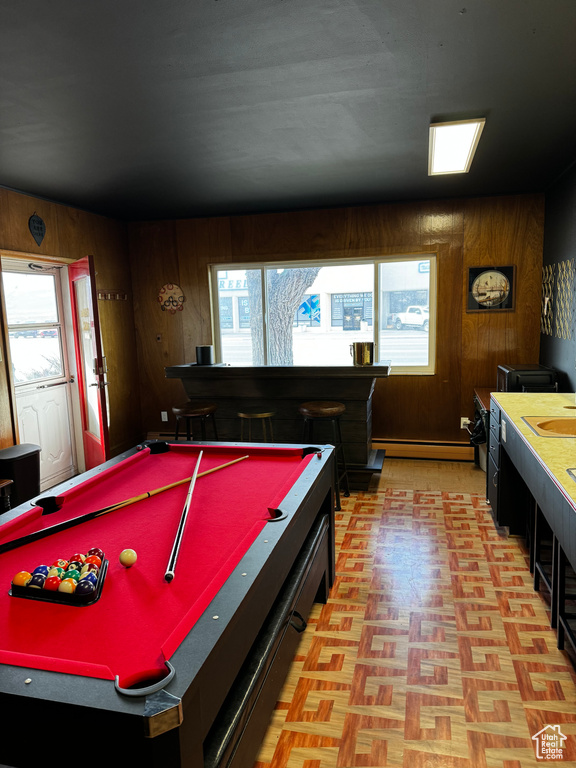 Recreation room with a baseboard heating unit, wood walls, billiards, and light parquet floors