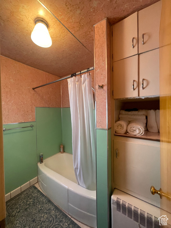 Bathroom with shower / tub combo with curtain, radiator, and tile floors
