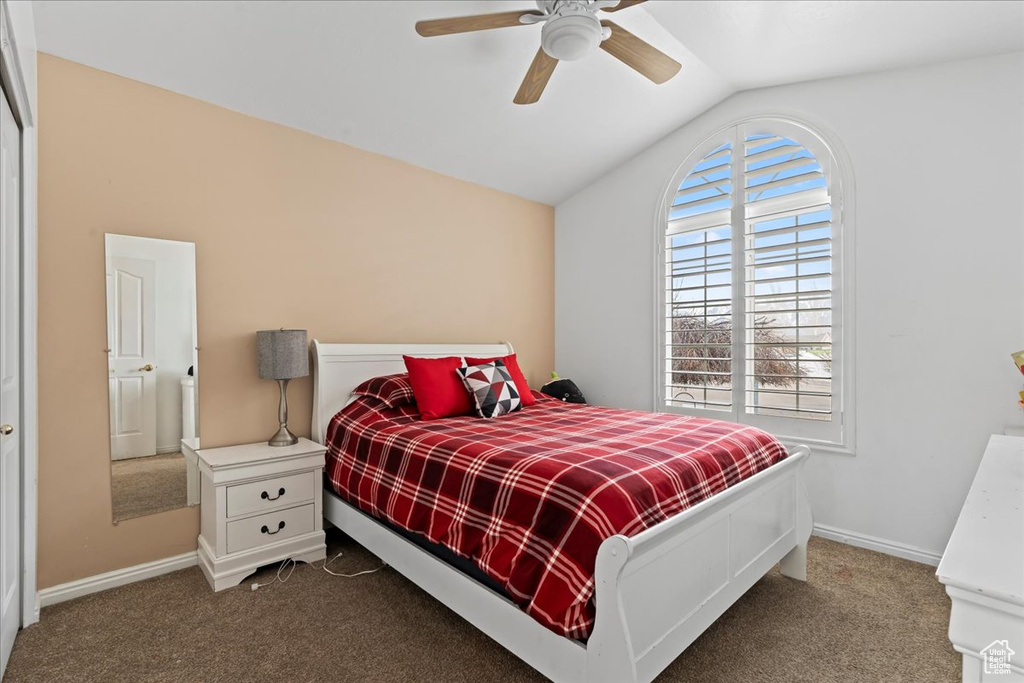 Bedroom with lofted ceiling, dark carpet, and ceiling fan
