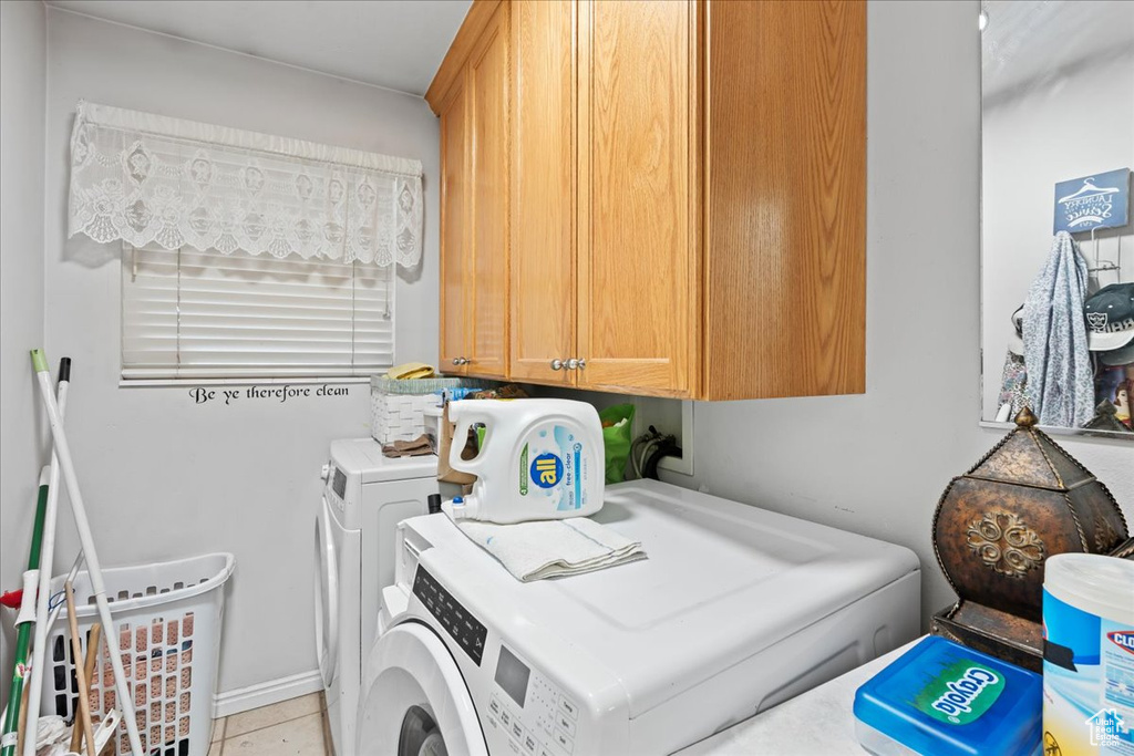 Laundry area featuring light tile floors, washer and dryer, and cabinets