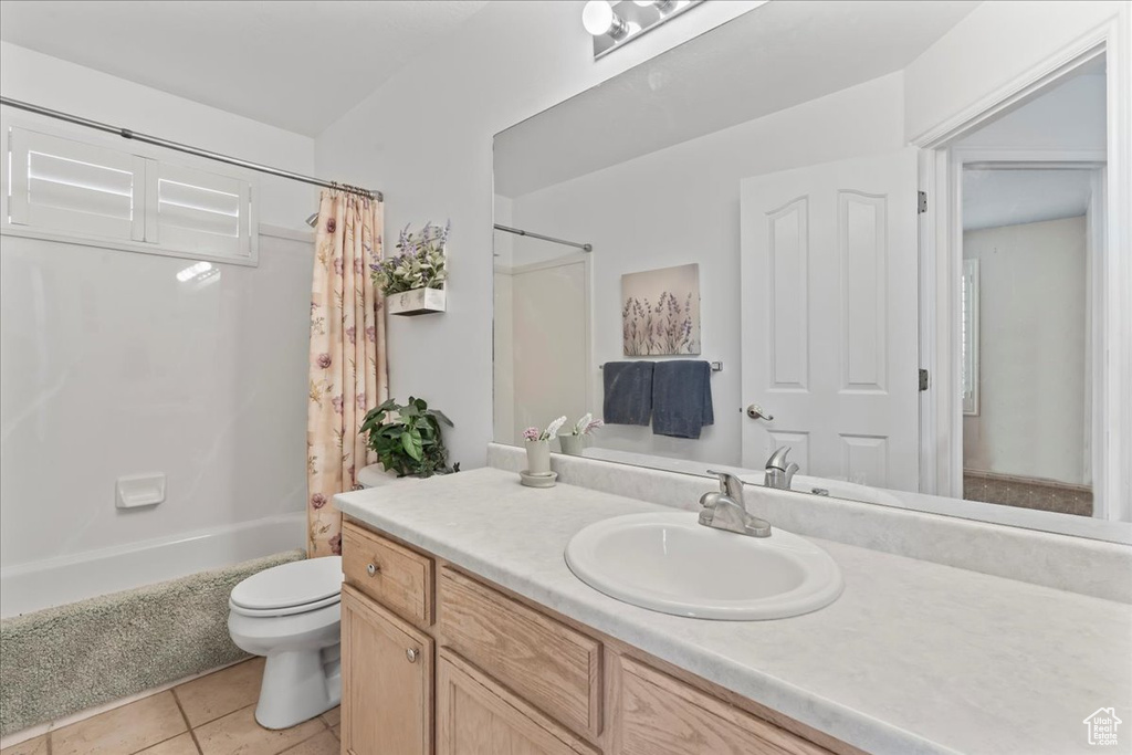 Full bathroom with tile flooring, vanity with extensive cabinet space, toilet, and shower / bathtub combination with curtain