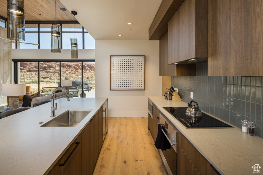 Kitchen featuring black electric stovetop, oven, modern cabinets, tasteful backsplash, and recessed lighting