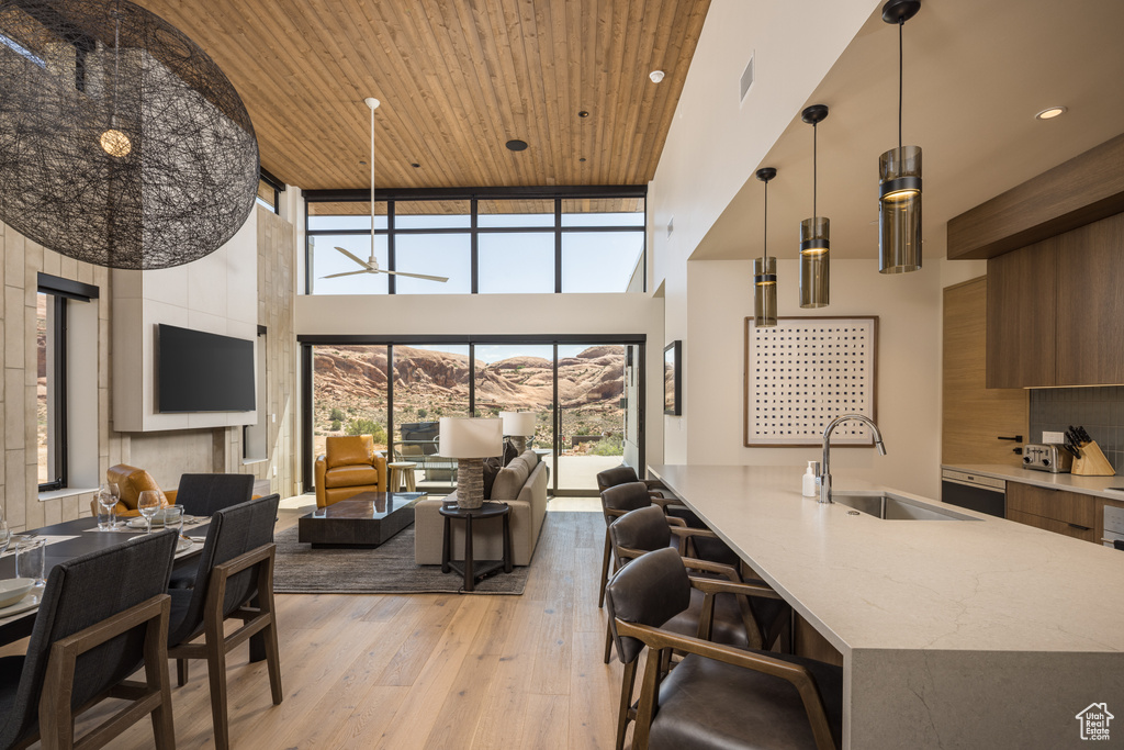 Kitchen with a towering ceiling, modern cabinets, light wood-type flooring, open floor plan, and tasteful backsplash