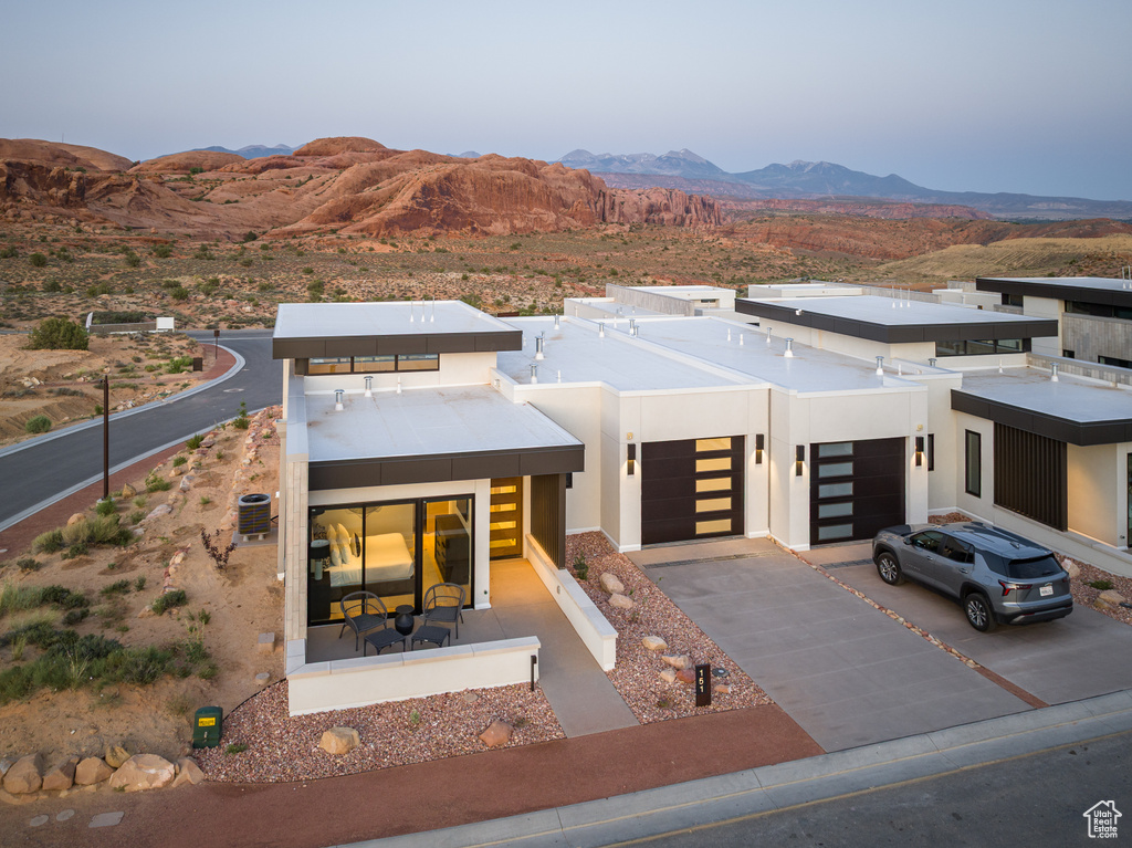 Modern home featuring a mountain view, a garage, concrete driveway, and stucco siding