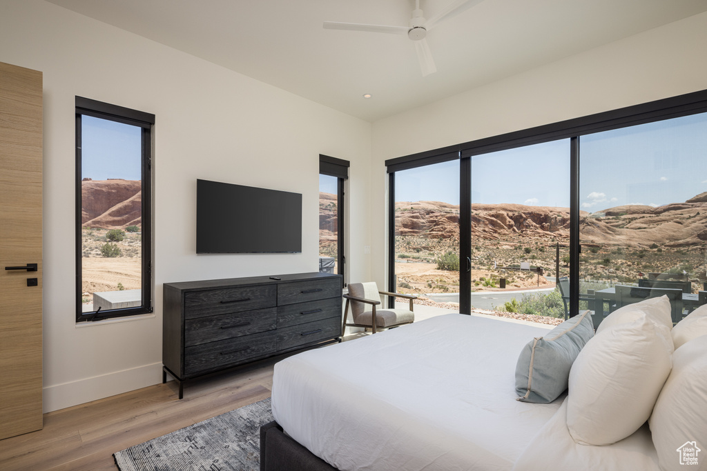 Bedroom with multiple windows, light wood-style flooring, and ceiling fan