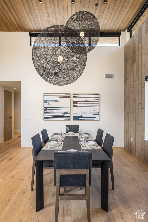 Dining area with wooden ceiling, wood finished floors, and a high ceiling