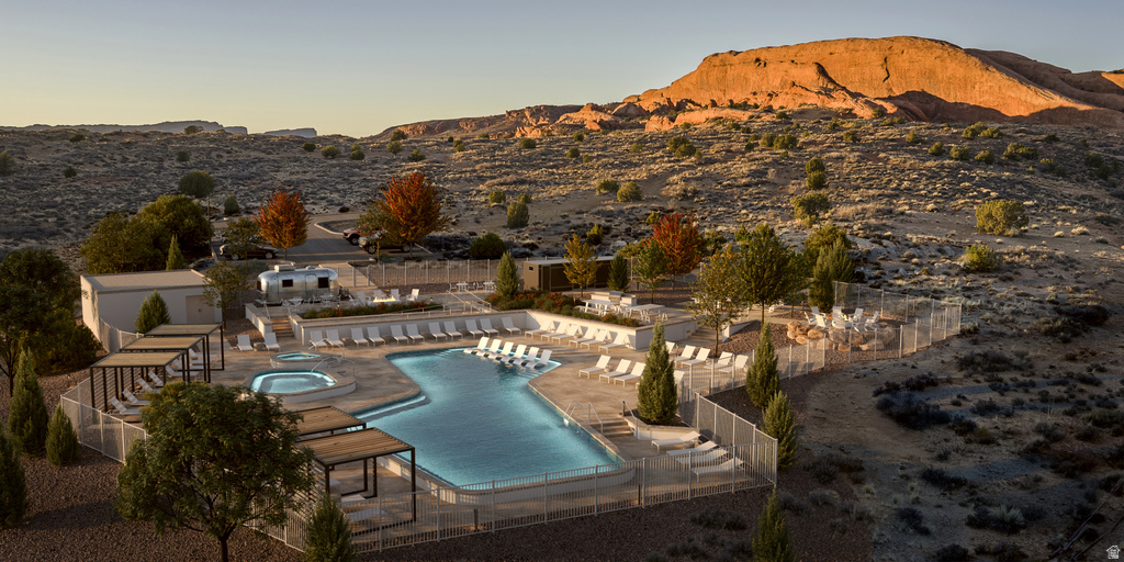 Pool at dusk with a patio area, a community pool, a community hot tub, and a mountain view