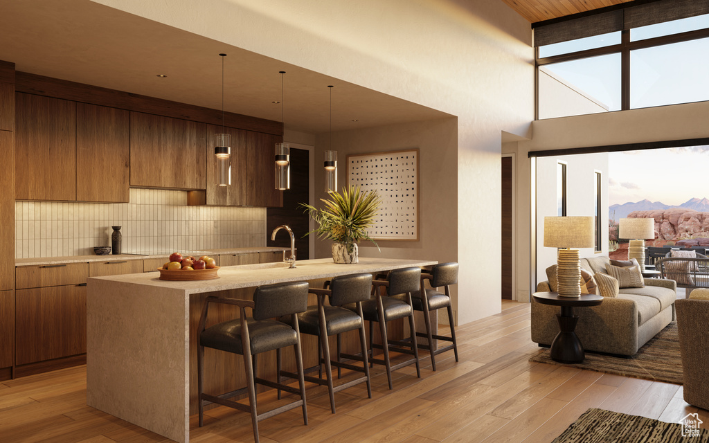 Kitchen featuring a high ceiling, backsplash, a breakfast bar area, light hardwood / wood-style floors, and sink