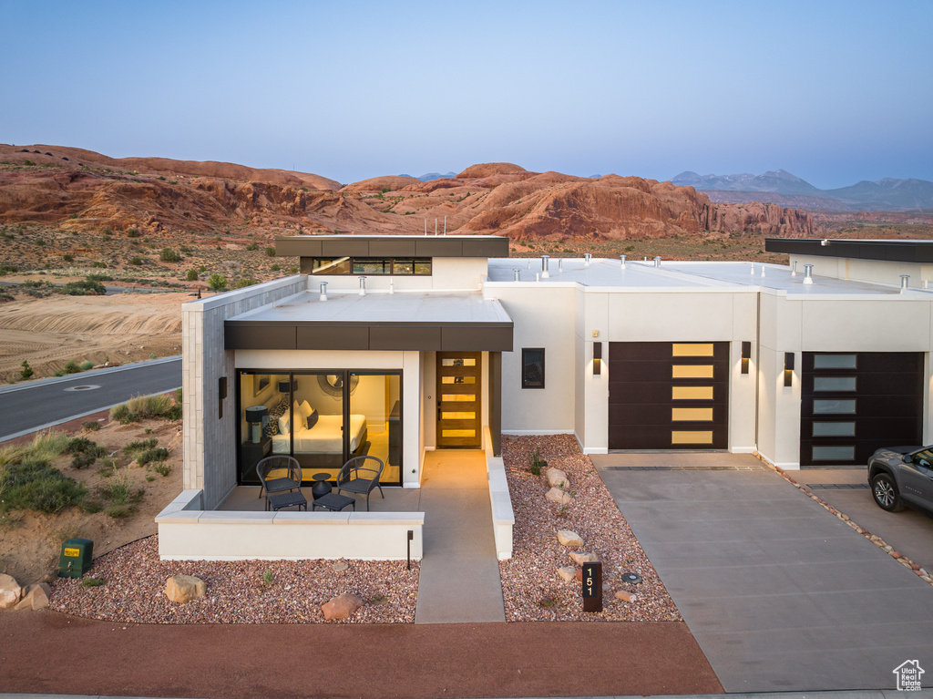 Contemporary home featuring a mountain view, stucco siding, concrete driveway, and an attached garage