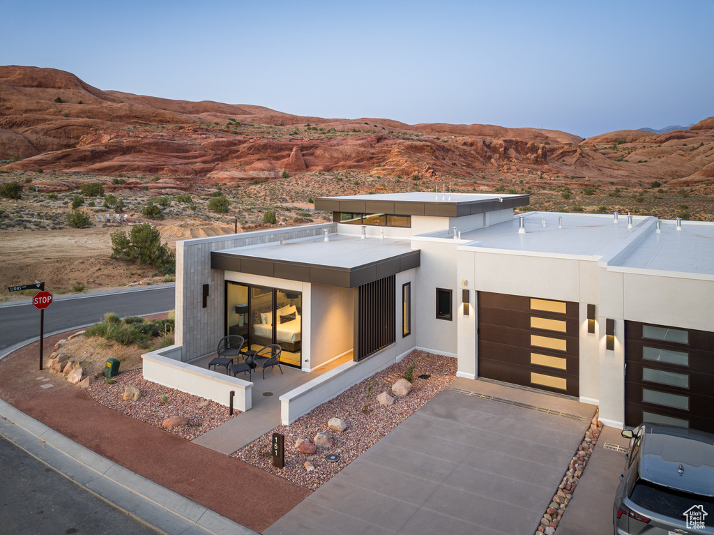 Contemporary house with a mountain view, concrete driveway, an attached garage, and stucco siding