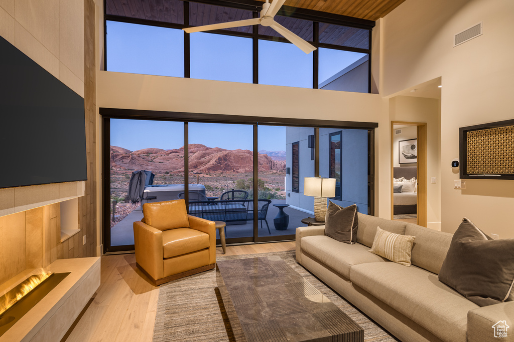 Living area with wood finished floors, a mountain view, and a towering ceiling