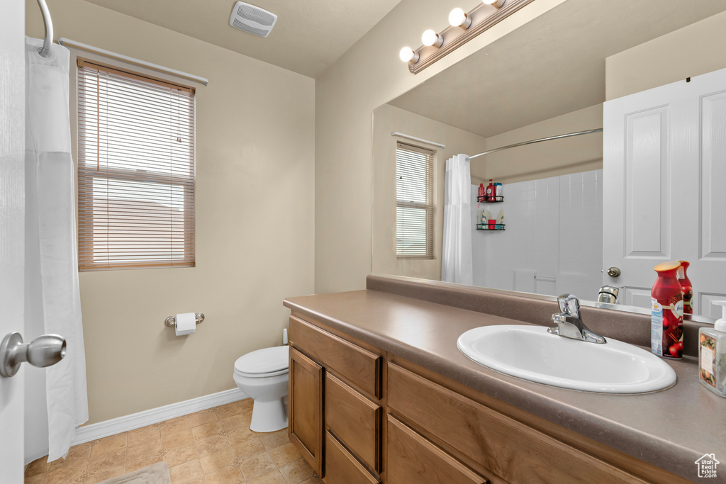 Bathroom with toilet, vanity, and a healthy amount of sunlight