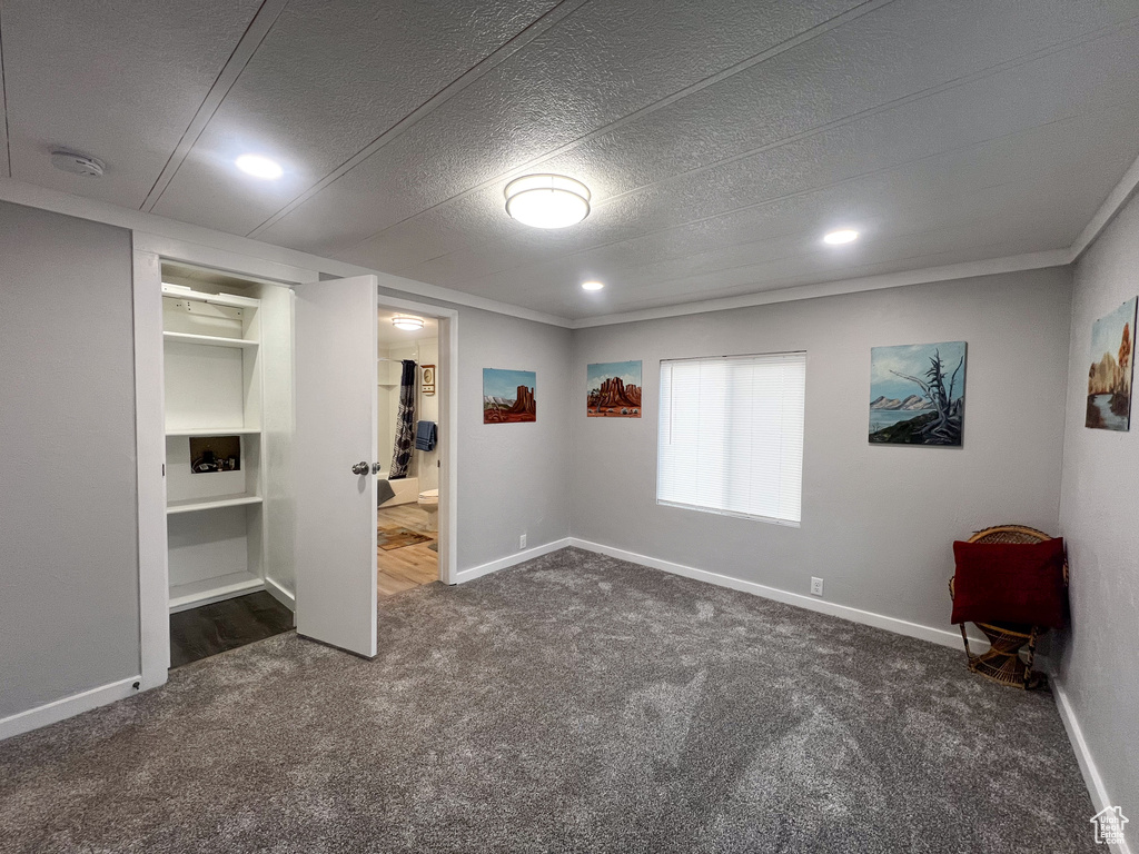 Unfurnished bedroom featuring connected bathroom, a textured ceiling, and dark carpet