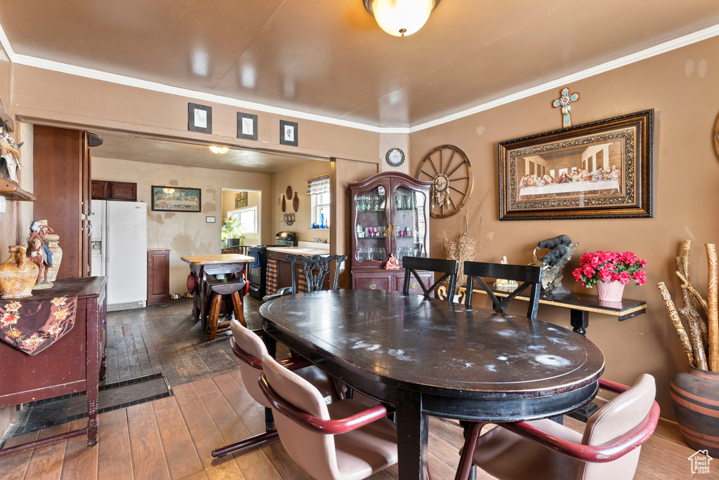 Dining space with ornamental molding and dark wood-type flooring