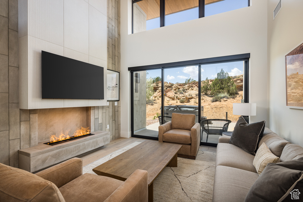 Living area featuring a towering ceiling, a tile fireplace, and light wood-type flooring